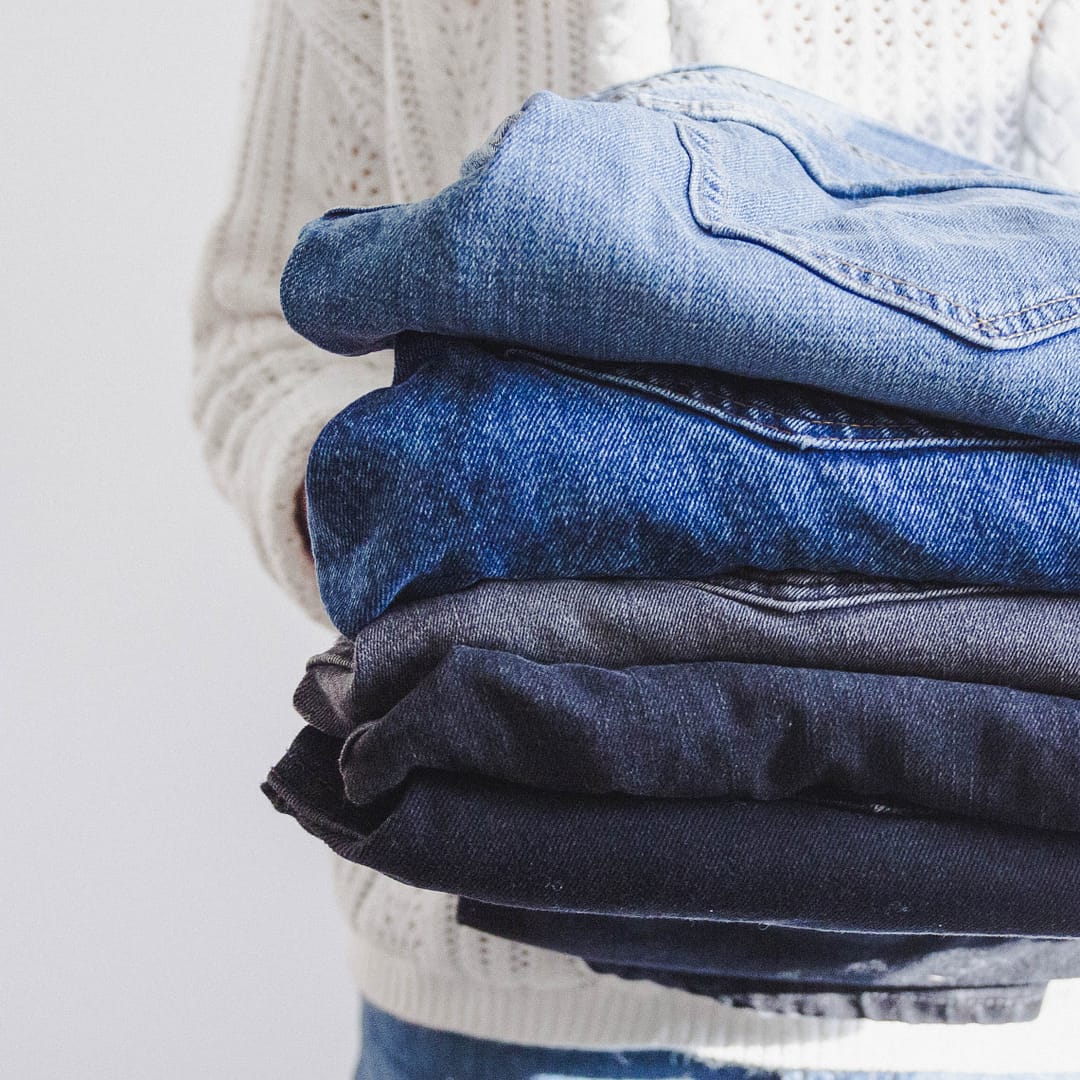 Woman holding a stack of folded jeans