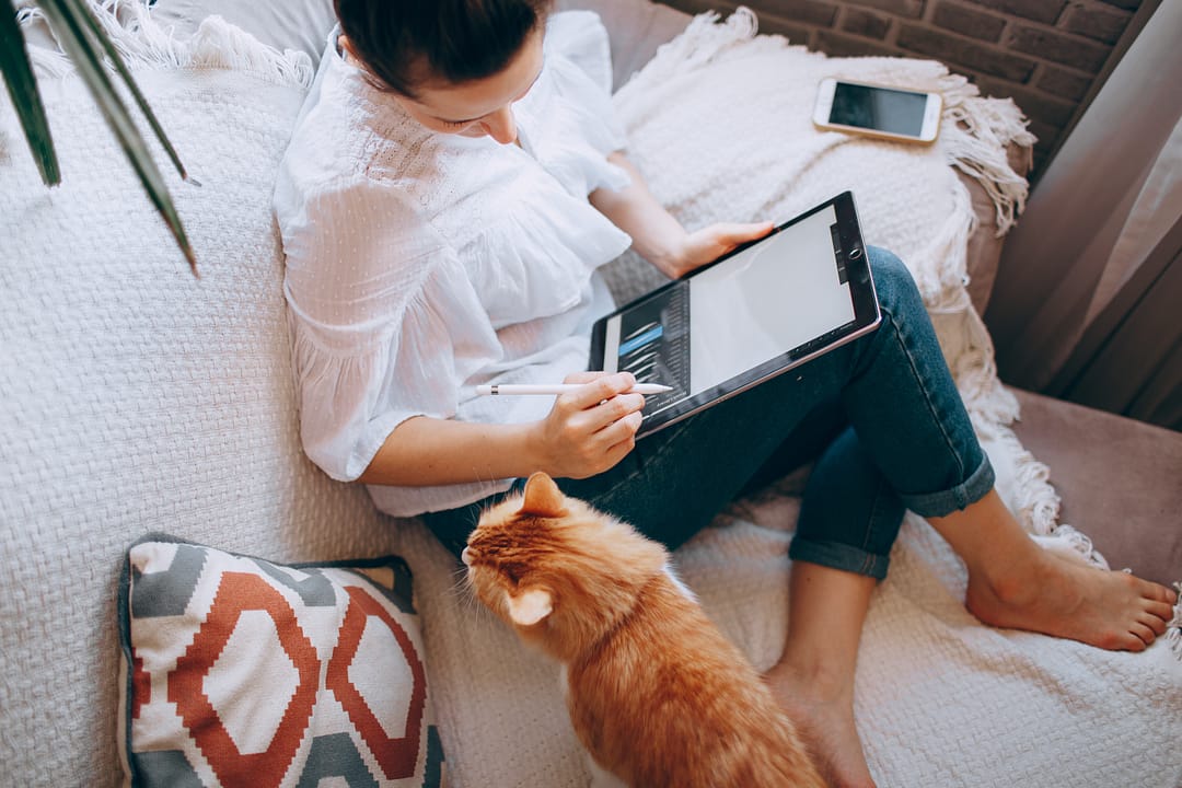 Woman looking at a financial report on a tablet while sitting on her couch