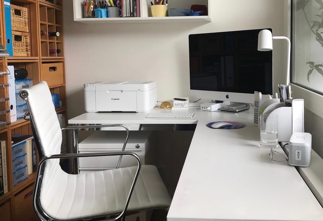 White canon printer on a minimal white desk in a small office